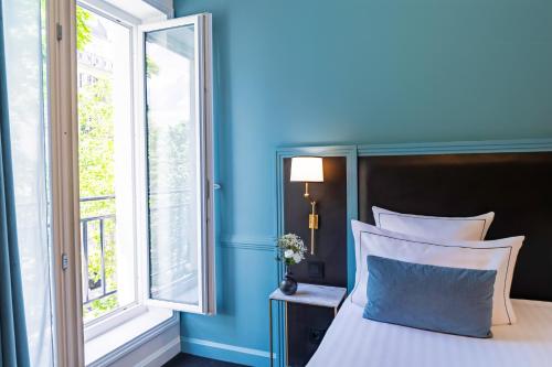 a bedroom with blue walls and a bed with a window at Hôtel Le Cercle Tour Eiffel in Paris