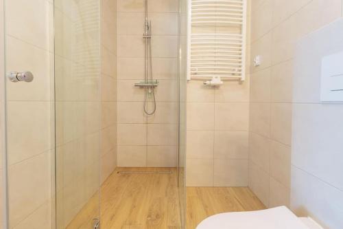 a bathroom with a shower with a toilet and a window at VacationClub - Moon Residence Apartament 12 in Ustronie Morskie