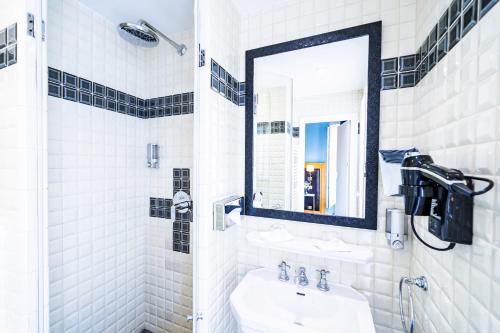 a white bathroom with a sink and a mirror at Hôtel Le Cercle Tour Eiffel in Paris