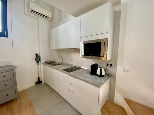 Il comprend une petite cuisine blanche avec un évier et un four micro-ondes. dans l'établissement Studio Beautes FSHH, à Nice