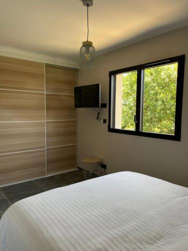 une chambre avec un lit blanc et une fenêtre dans l'établissement Petite villa paisible, à Hyères
