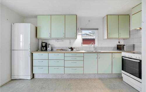 a kitchen with green cabinets and a white refrigerator at Holiday Home Huginsvej in Slagelse