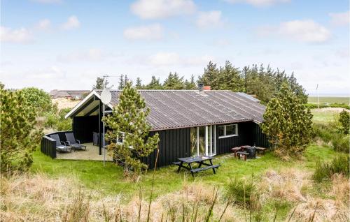 a small black cabin with a picnic table in a field at Three-Bedroom Holiday Home In Hvide Sande in Hvide Sande