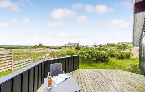 a table and chair on a deck with a view of the beach at Three-Bedroom Holiday Home In Hvide Sande in Hvide Sande