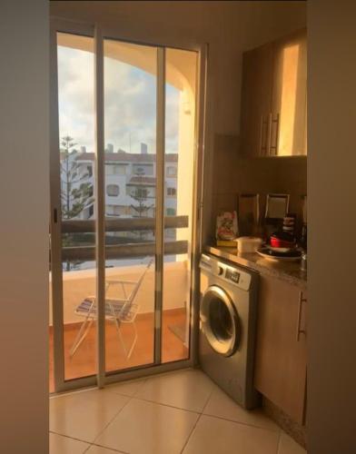 a kitchen with a washing machine and a balcony at Appartement t3 à sidi Rahal in Sidi Rahal