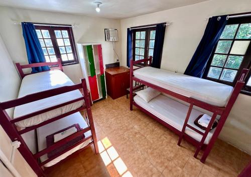 a room with two bunk beds and two windows at Hostel e Pousada Barra da Tijuca in Rio de Janeiro