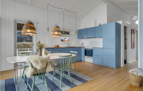 a kitchen with blue cabinets and a table and chairs at Holiday Home Bygmarken Sjølund Denm in Sjølund