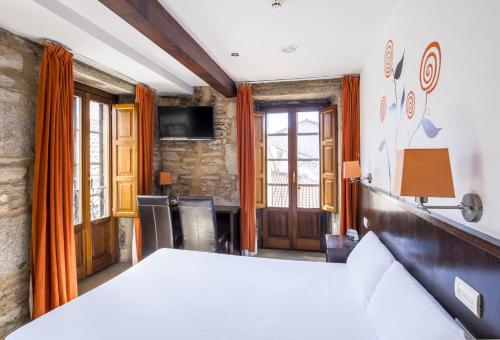 a bedroom with a large bed and a desk at Hotel Alda Algalia in Santiago de Compostela