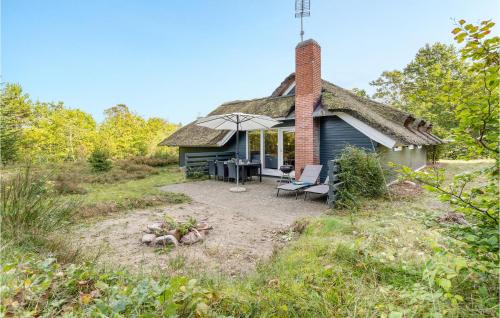 a small house with a thatched roof sitting in a field at Stråhatten in Glesborg