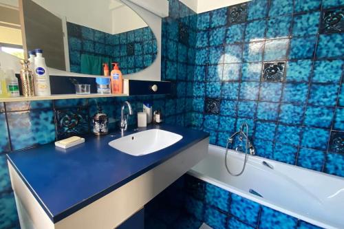 une salle de bain carrelée bleue avec un lavabo et une baignoire dans l'établissement Magnifique villa avec piscine, à La Grande Motte