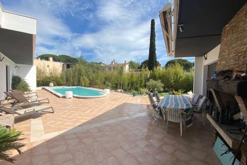 un patio avec une table et des chaises et une piscine dans l'établissement Magnifique villa avec piscine, à La Grande Motte