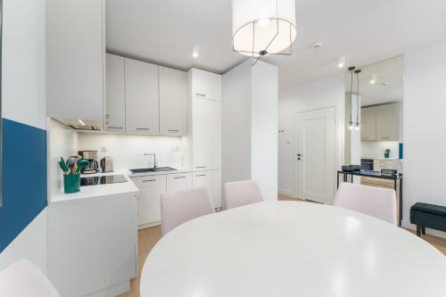 a kitchen with white cabinets and a table and chairs at FARO Apartamenty Polanki Aqua SPA Deluxe 4 baseny w cenie, Pools inklusive in Kołobrzeg