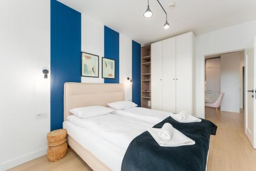 a bedroom with a white bed and blue walls at FARO Apartamenty Polanki Aqua SPA Deluxe 4 baseny w cenie, Pools inklusive in Kołobrzeg