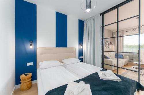 a bedroom with a large bed with blue walls at FARO Apartamenty Polanki Aqua SPA Deluxe 4 baseny w cenie, Pools inklusive in Kołobrzeg