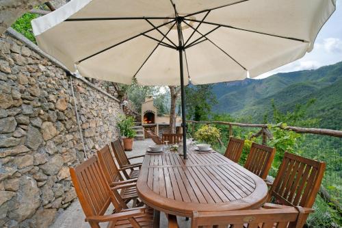 a wooden table and chairs with an umbrella at Agriturismo U' Spigu Nonna Annetta in Nasino