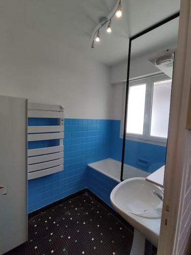 La salle de bains bleue et blanche est pourvue d'un lavabo et d'un miroir. dans l'établissement Maison de vacances Berck-Plage, à Berck-sur-Mer