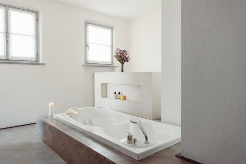 a bath tub in a white bathroom with two windows at Scarpa Villas - Barolo Luxury Escape in Verduno