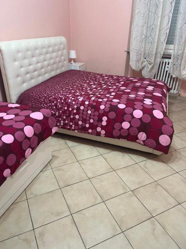 Una cama morada con sábanas de lunares. en centro storico Asti Monferrato Langhe, en Asti