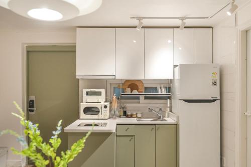 a kitchen with white cabinets and a white refrigerator at Emotional, 3type inteior style in Seoul