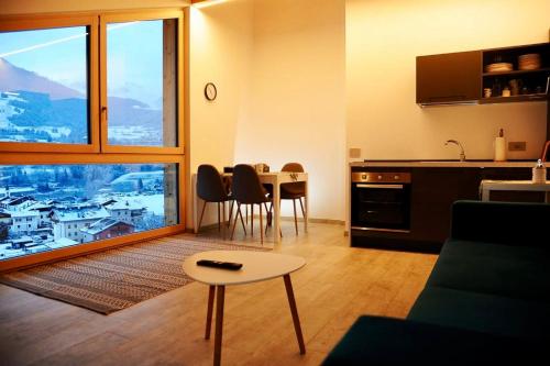 a living room with a table and a kitchen with a view at Lagorai Suites in Cavalese