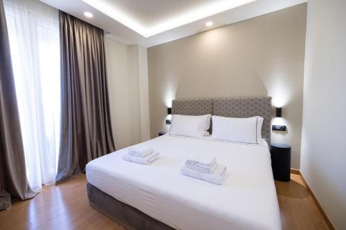a bedroom with a large white bed with two towels on it at Green Boutique Hotel in Vlorë