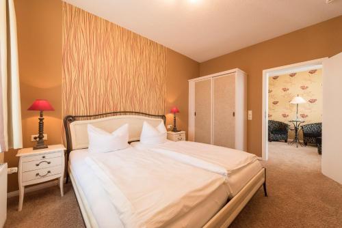 a bedroom with a large bed with white sheets and pillows at Hotel Villa Waldfrieden in Ostseebad Sellin