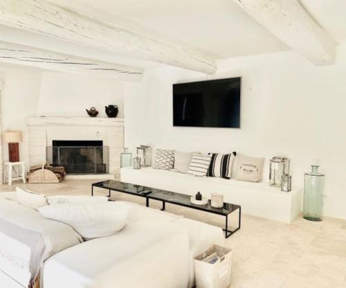 un salon blanc avec un canapé blanc et une télévision dans l'établissement Le Moulin, à Saint-Vallier-de-Thiey