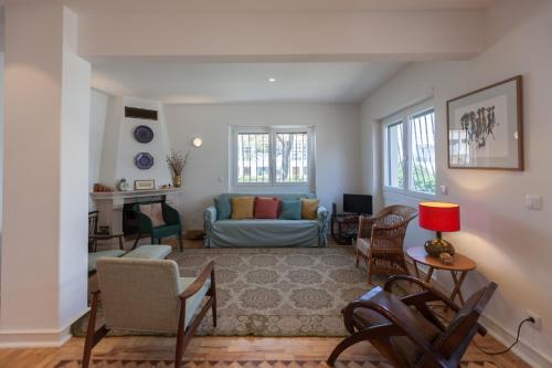 ein Wohnzimmer mit Couch und Stühlen in der Unterkunft FLH Jacaranda Costa Caparica Beach House in Costa da Caparica