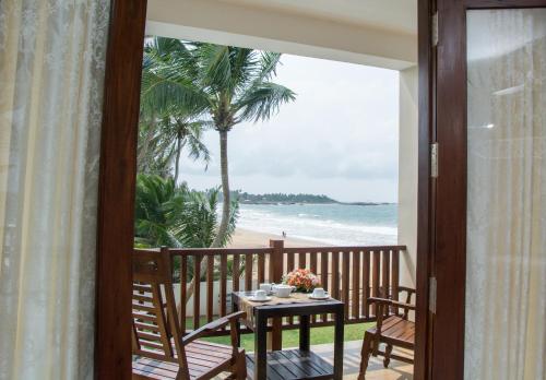 a balcony with a table and chairs and the beach at Sapphire Seas Beachfront Hotel in Hikkaduwa