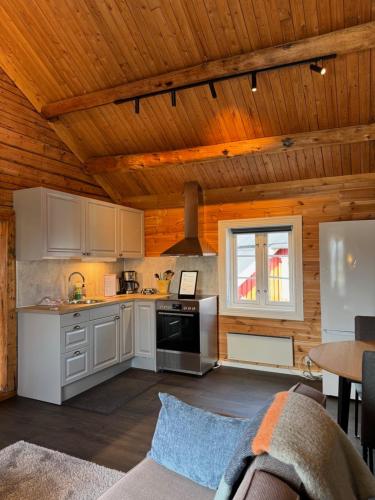 a kitchen with white cabinets and a wooden ceiling at Toppøy Rorbuer in Reine
