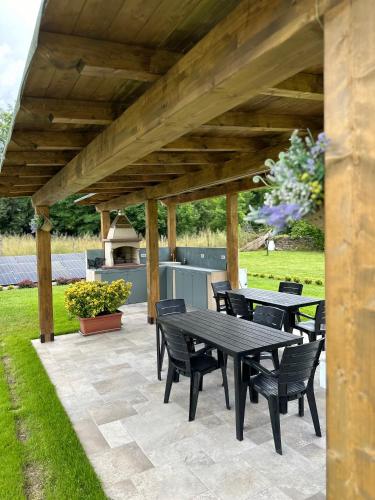 a patio with tables and chairs under a wooden pergola at Villa Amanda in Scorcetoli