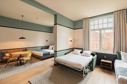 a hotel room with two beds and a table at Getaway Studios Gent in Ghent