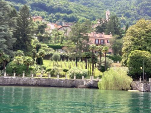 a house on a hill next to a body of water at wonderful lake front appartment near Bellagio in Limonta