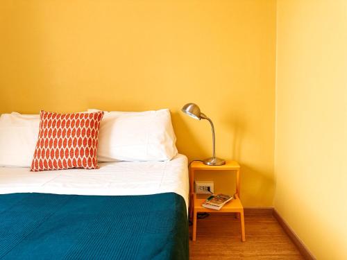 a bedroom with a bed with a lamp on a side table at Ostello Bello Milano Centrale in Milan