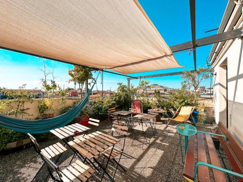 a patio with a hammock and tables and chairs at Ostello Bello Milano Centrale in Milan
