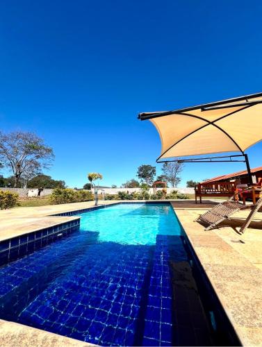 a swimming pool with an umbrella and a table at pousada vila das oliveiras in Pirenópolis