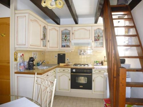 une cuisine avec des armoires blanches et un four noir dans l'établissement Villa 4 pers avec climatisation proche plages - V0727, à Vias