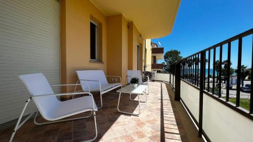three white chairs and a table on a balcony at Appartamento incantevole a due passi dal mare 3 in Alba Adriatica