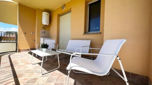 two white chairs and a table on a balcony at Appartamento incantevole a due passi dal mare 3 in Alba Adriatica