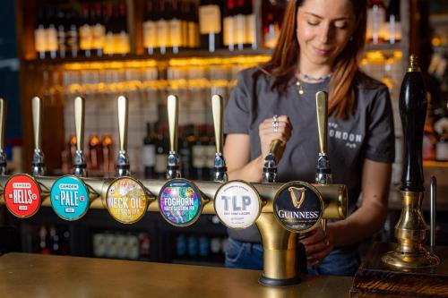 a woman standing behind a bar with a bottle of alcohol at Royal National Hotel in London