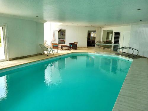 une grande piscine bleue dans une maison dans l'établissement Villa bord de mer La Mielle, à Créances