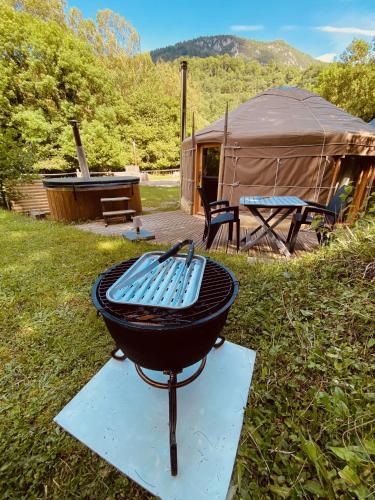 a grill in the grass with a tent in the background at Yourte et son bain nordique in Fréchet-Aure