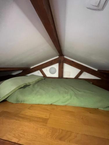 Cette chambre comprend un lit vert et du parquet. dans l'établissement Maisonnette de 34m2 proche de la Gare, à Houilles
