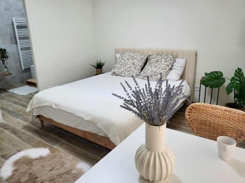 - une chambre avec un lit et un vase sur une table dans l'établissement Romance studio hyper centre, à Saint-Étienne