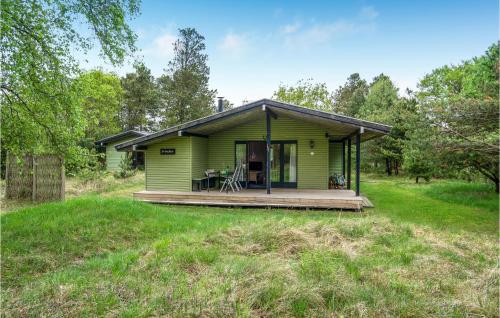 a green house with a porch in a field at Brincken in Vejers Strand