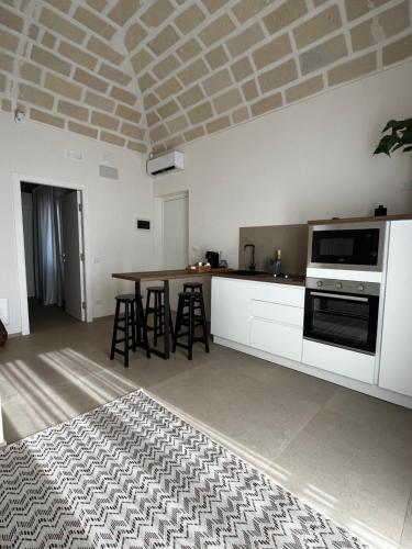 a kitchen with white cabinets and a table with stools at Acqua Salmastra Apartment in Favignana