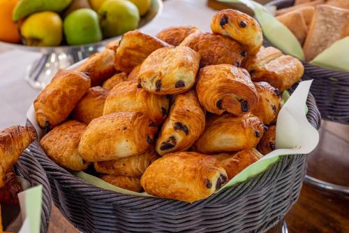una cesta de cruasanes y otros pasteles en una mesa en Logis Hotel Noemys pont de l'Etoile, en Aubagne