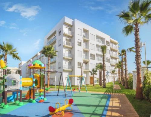 a playground in front of a building with palm trees at Shems Bouznika kettani in Bouznika