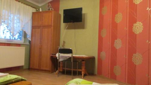 a bedroom with a desk and a tv on a wall at Zajazd U Renaty in Poraj
