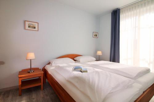 a bedroom with two beds with white sheets and a window at Villa Rosita Fewo 5 - SANDKÖRNCHEN in Rerik